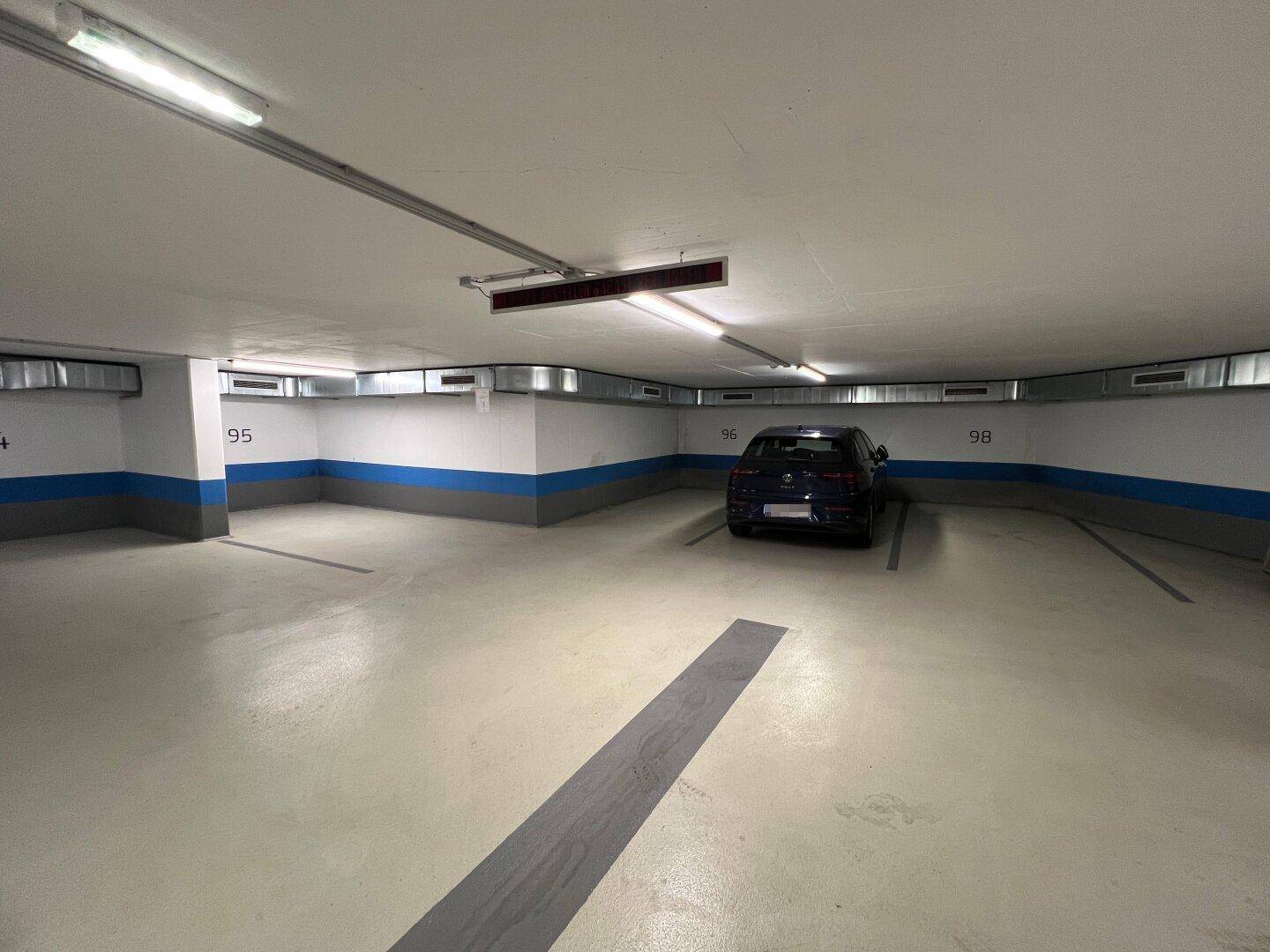 Mehrere Stellplätze in der Tiefgarage, einer davon belegt, mit guter Beleuchtung und Markierungen.