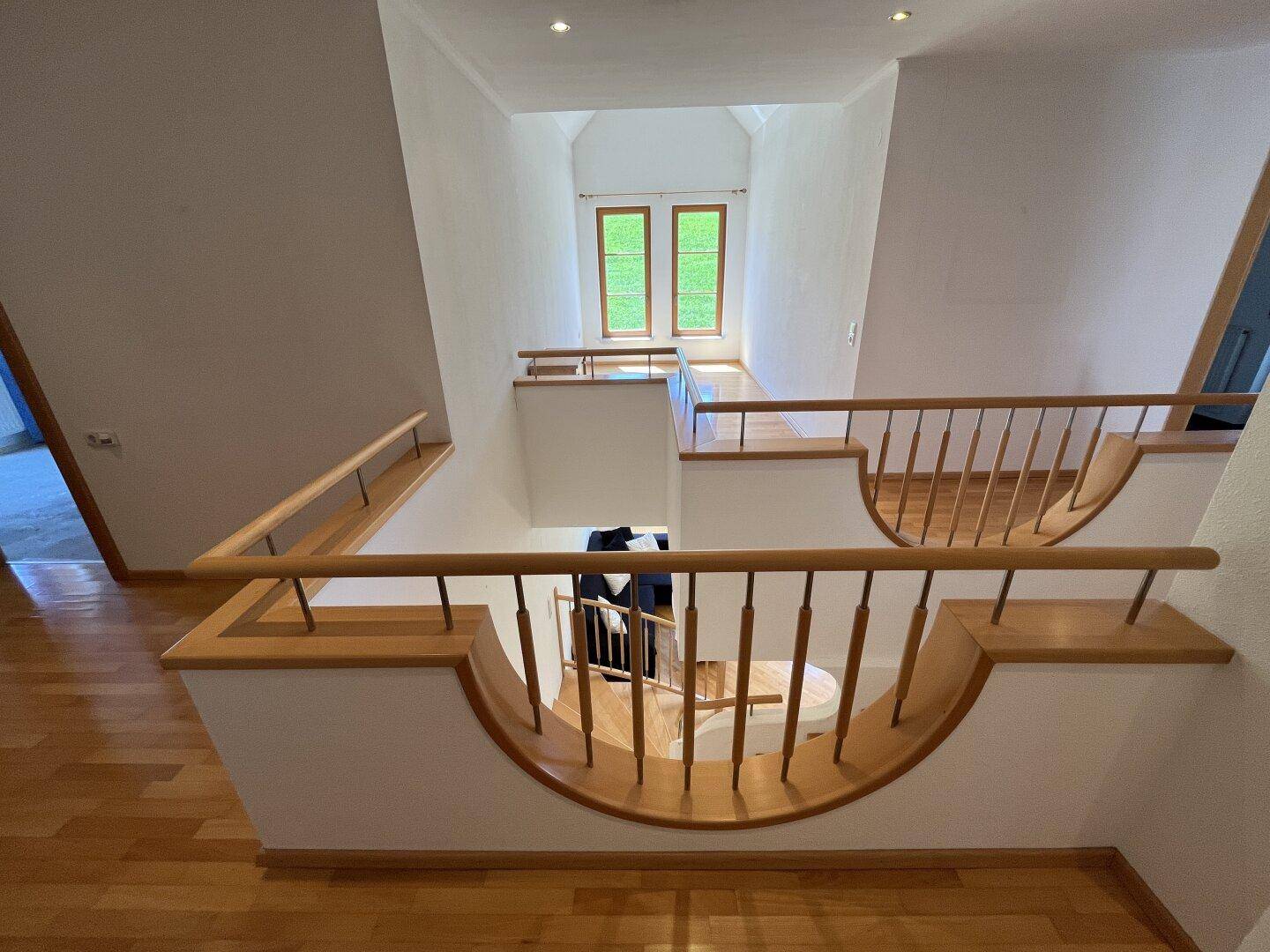 Heller Treppenaufgang mit Holzgeländer und Blick auf die oberen Etagen des Hauses.