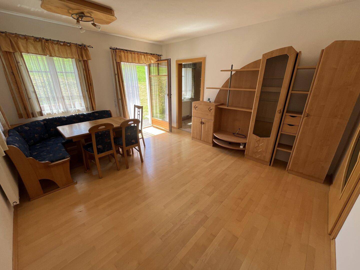 Geräumiger Wohn-Essbereich mit Holzfußboden, Esstisch und Zugang zum Garten.