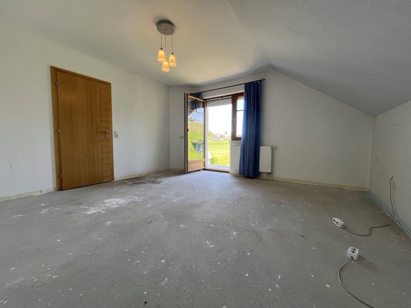 Unmöblierter Raum mit Betonboden und Zugang zu einem Balkon, bereit für die Gestaltung.
