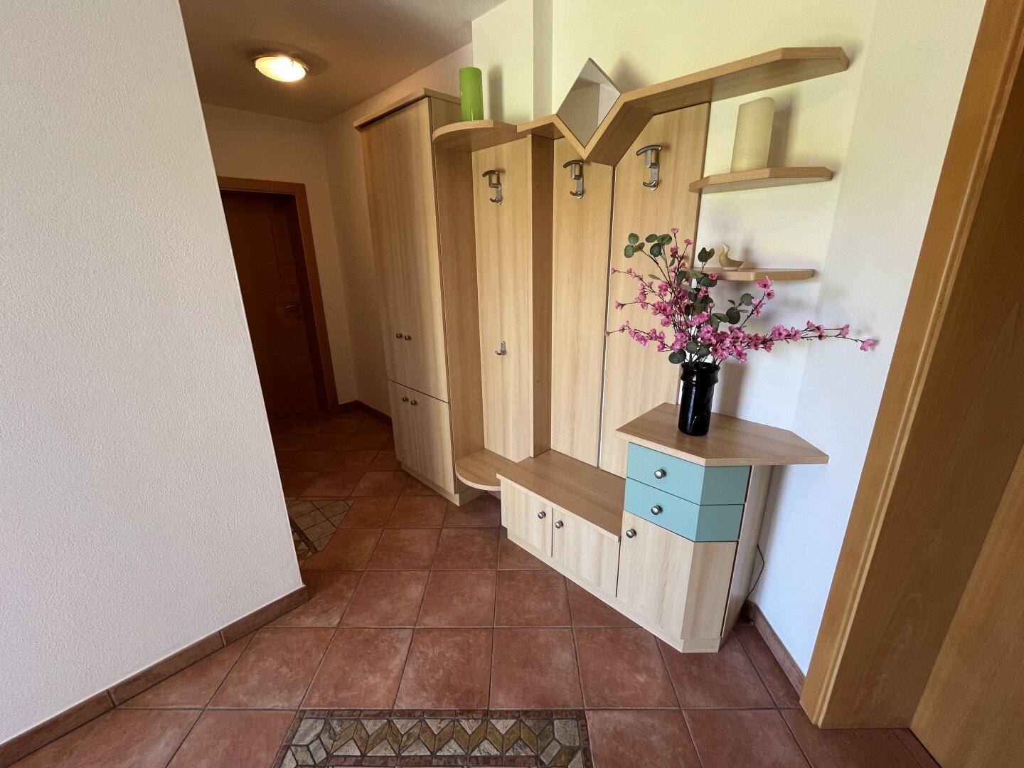 Gemütlicher Flur mit Holzgarderobe und Terrakotta-Fliesenboden, der zum Wohnbereich führt.