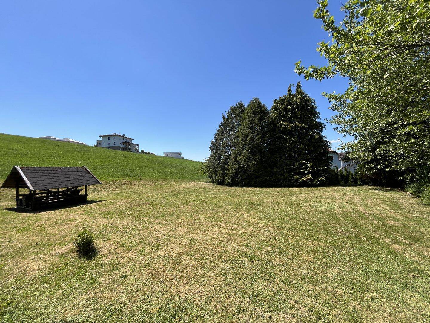 Großer Gartenbereich mit einer Holzlaube und weitem Blick auf die umliegende Landschaft.