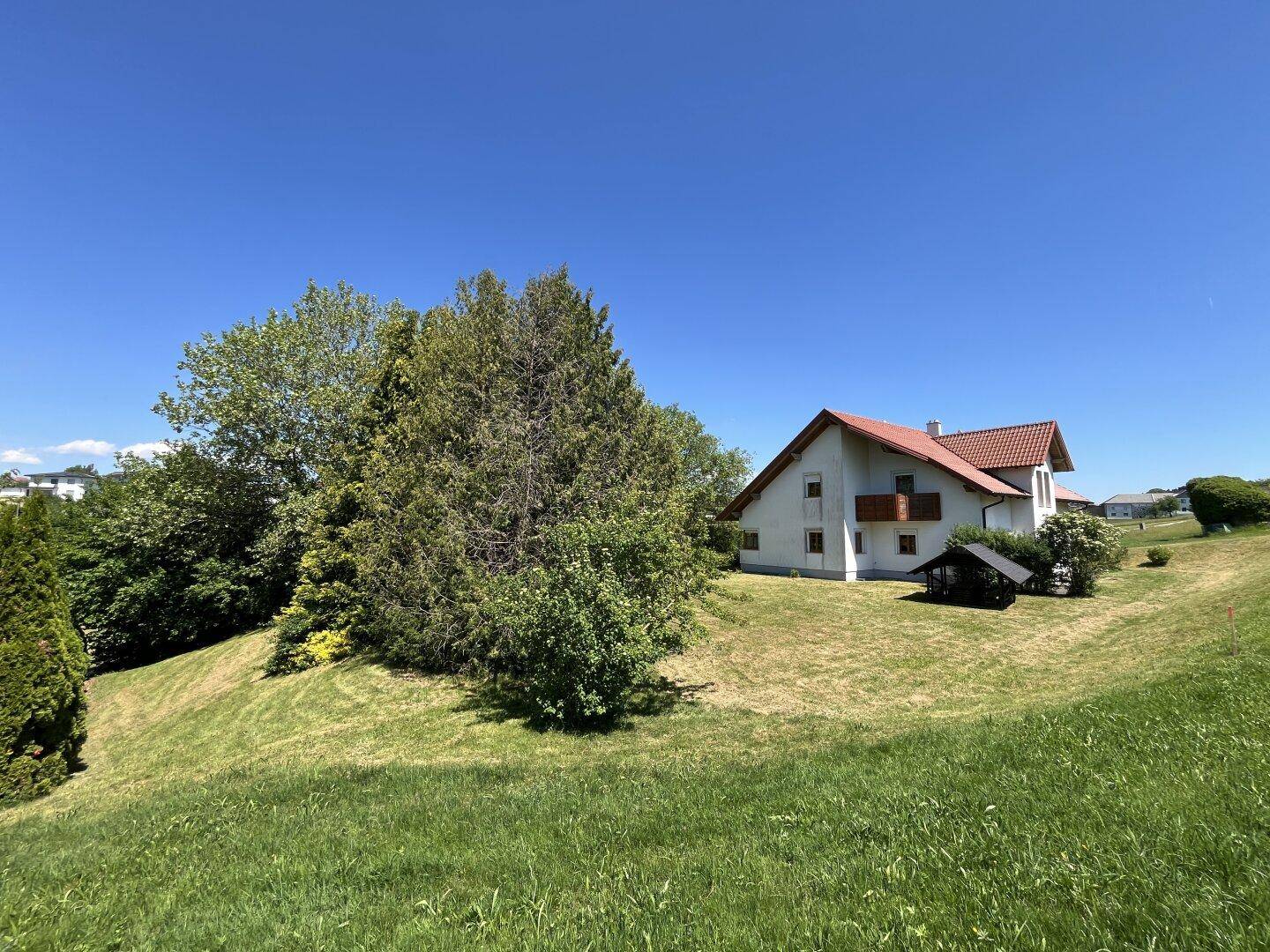 Weitläufige Ansicht des Hauses in ländlicher Umgebung mit viel Grün und Bäumen.