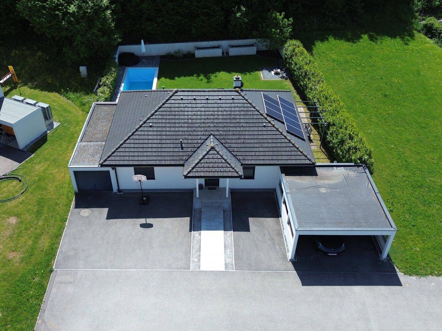 Vorderansicht des modernen Einfamilienhauses mit Carport, Garage und großzügiger Zufahrt.
