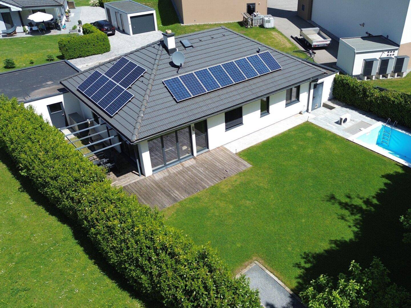 Luftaufnahme des Einfamilienhauses mit großem Garten, Swimmingpool und Photovoltaikanlage auf dem Dach.