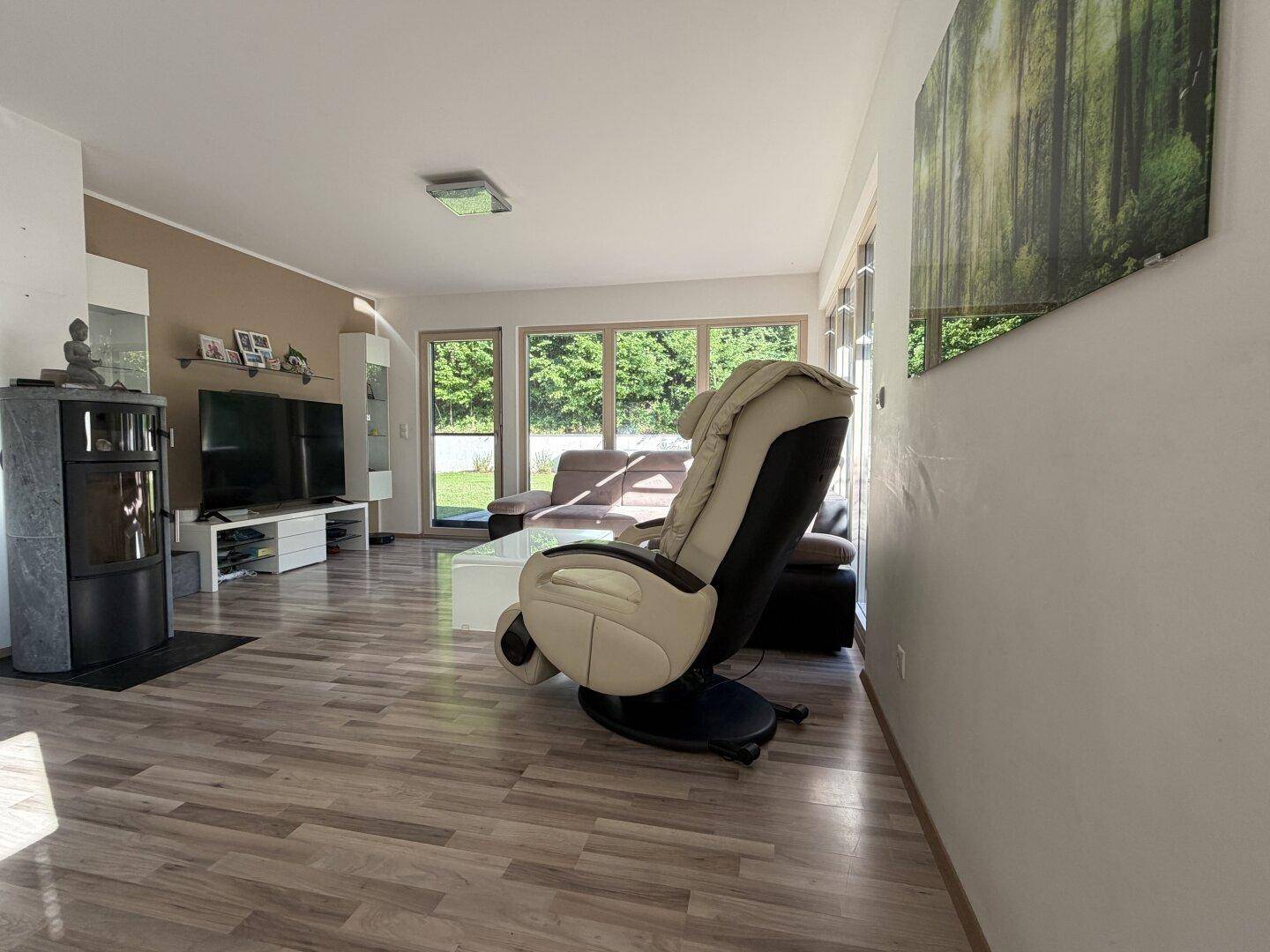 Gemütliches Wohnzimmer mit Kaminofen, Laminatboden und großen Fenstern zum Garten.