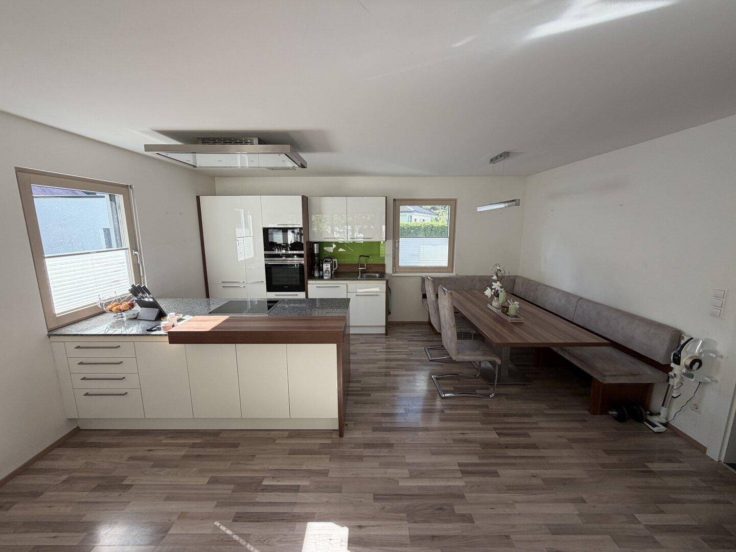 Moderne Einbauküche mit Kochinsel, Granitarbeitsplatte und integriertem Essbereich mit Sitzbank.