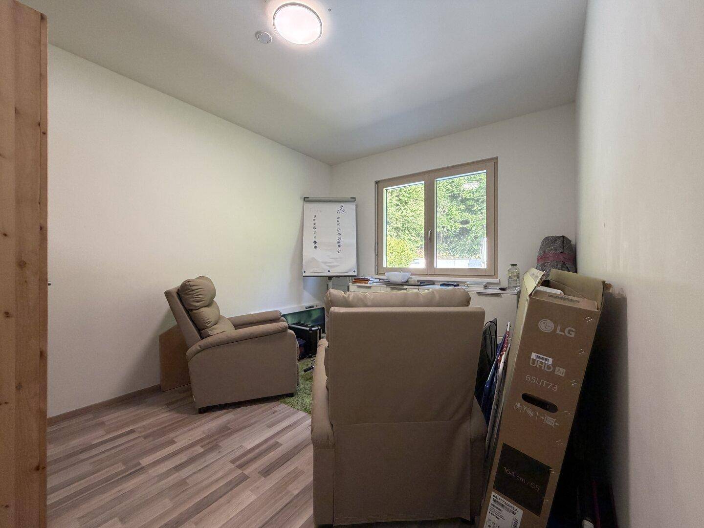Kleines Arbeitszimmer mit Laminatboden, Fenster und bequemen Sesseln, ideal für Home-Office.