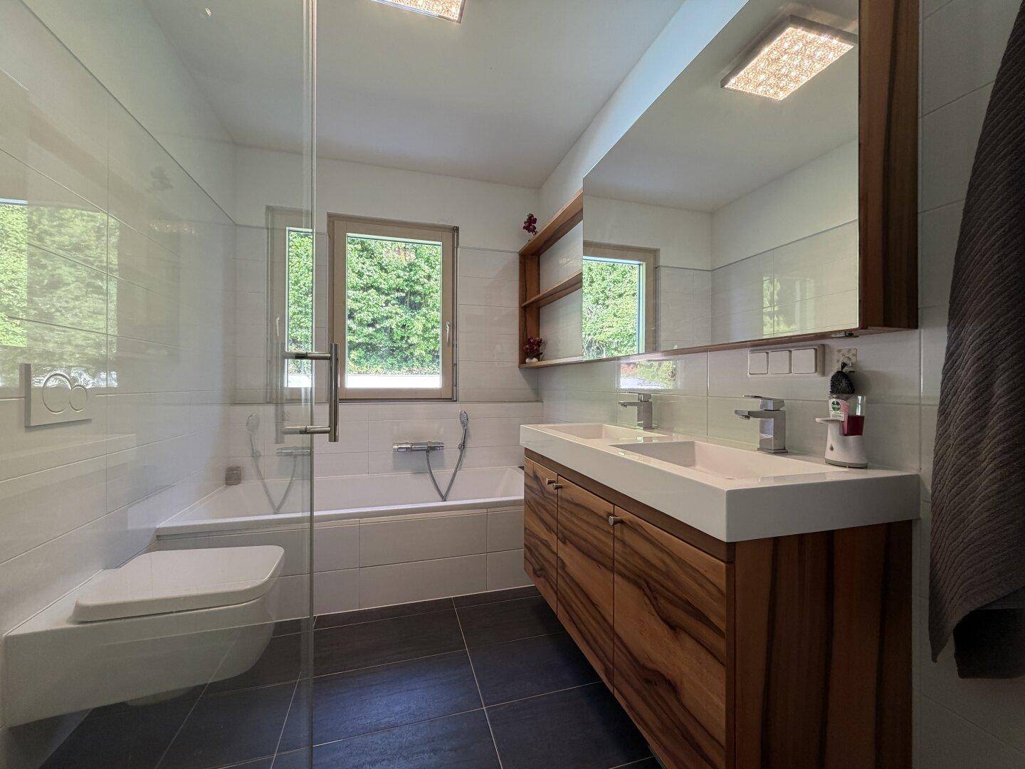 Helles Badezimmer mit Holzwaschtisch, Doppelwaschbecken, Badewanne und separater Glasdusche.