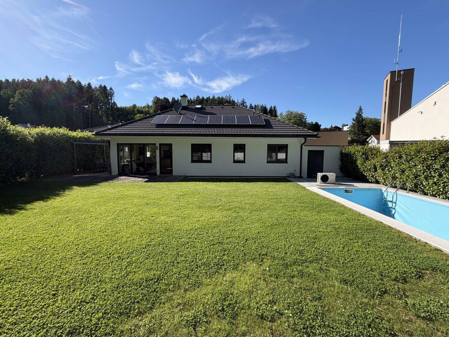 Rückansicht des Einfamilienhauses mit großem Garten, Swimmingpool und Photovoltaikanlage auf dem Dach.