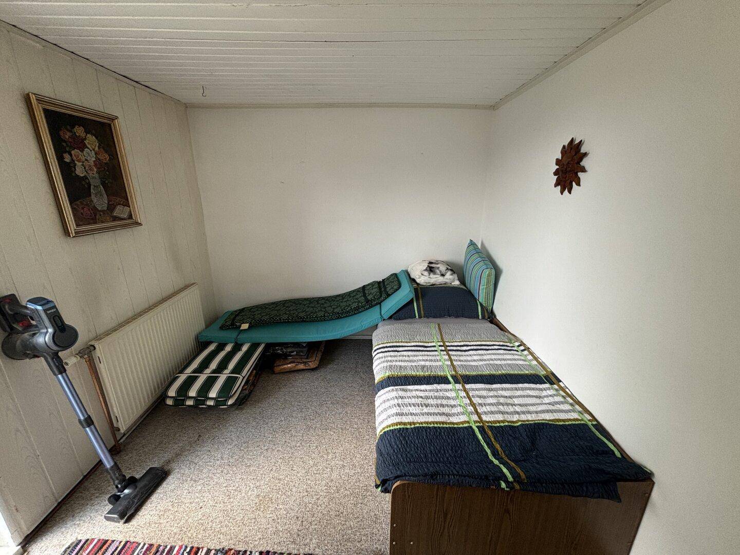 Schlichtes Schlafzimmer mit Teppichboden, Einzelbett und Heizkörper.