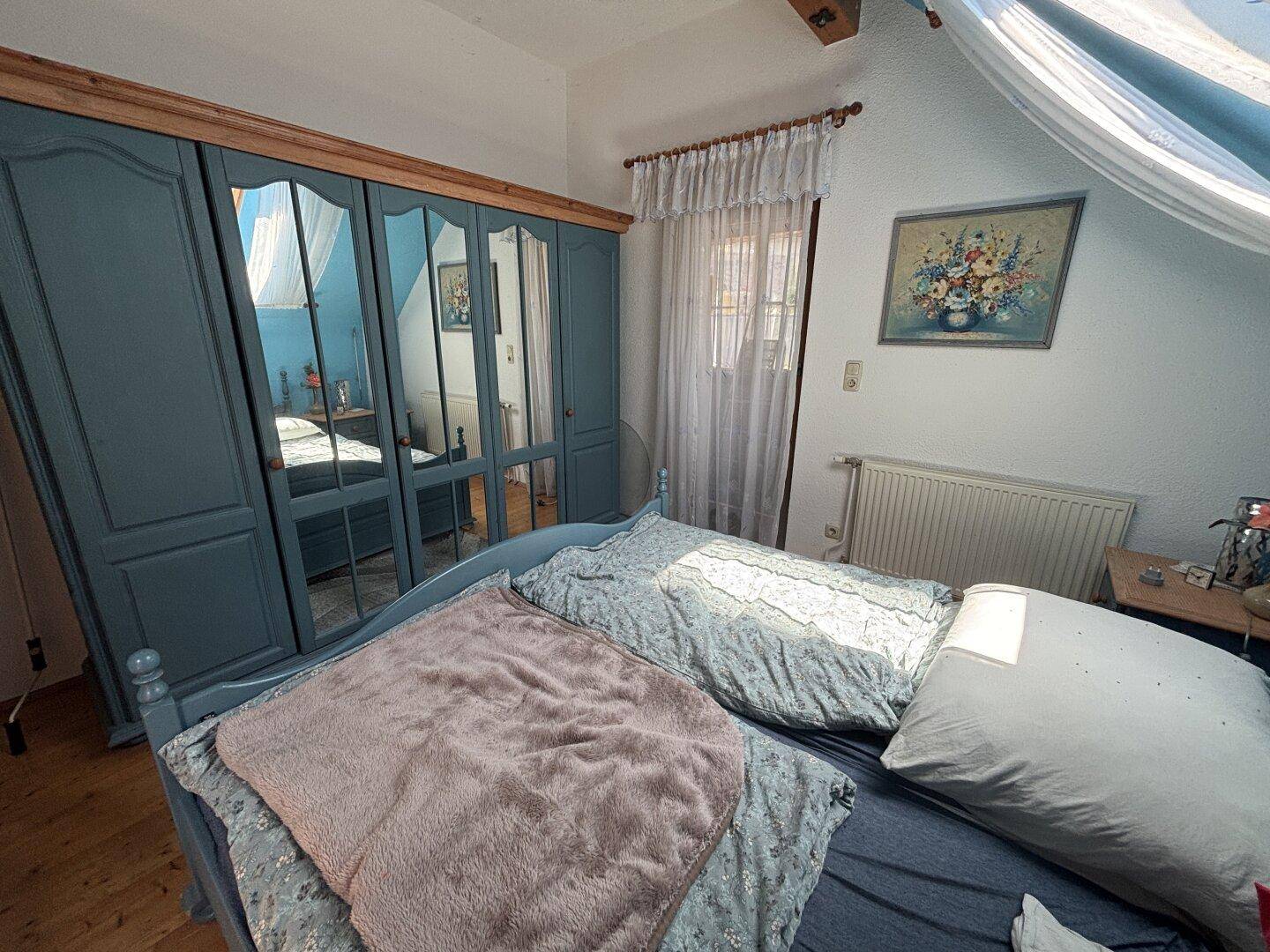 Schlafzimmer im Dachgeschoss mit großem Kleiderschrank und Holzboden.
