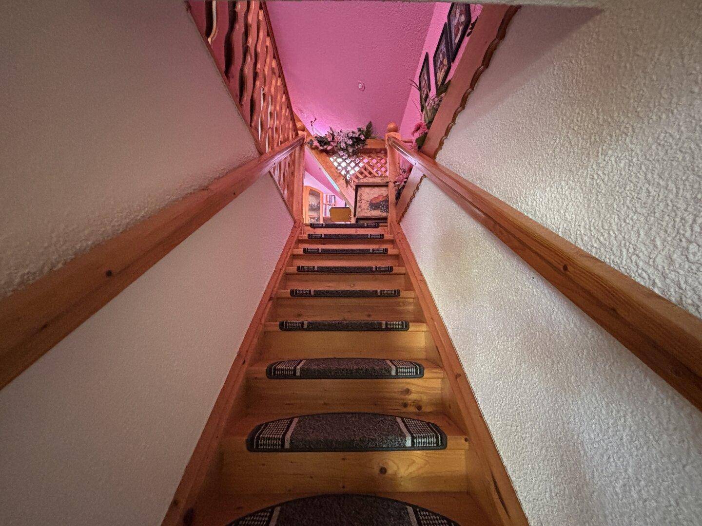 Holztreppe mit Teppichläufern führt in die obere Etage.