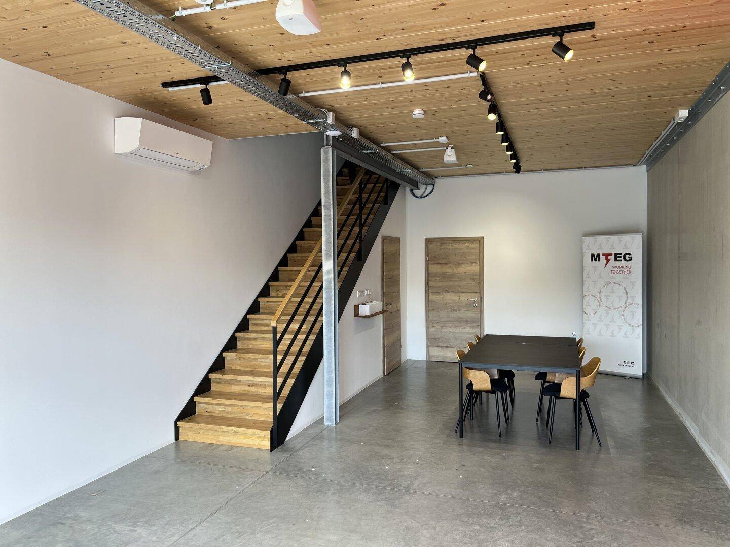 Moderner Empfangsbereich oder Büro mit Holztreppe, Holzbalkendecke und integrierter Beleuchtung.