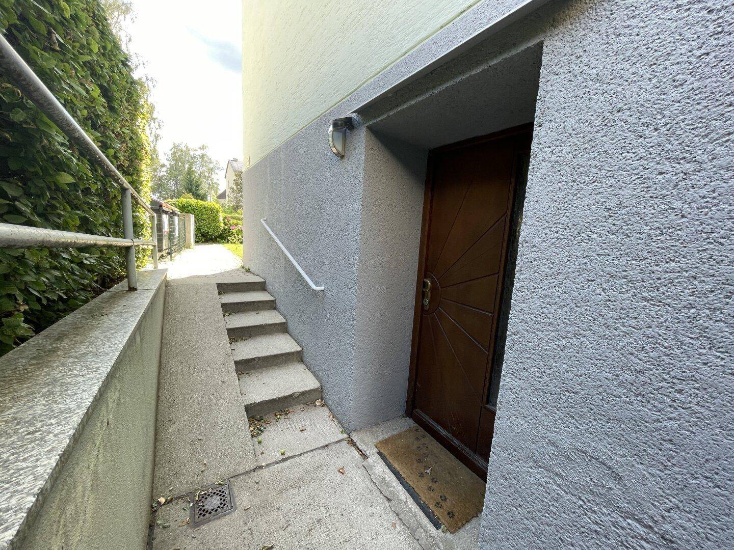 Seitlicher Eingangsbereich mit Treppe und Handlauf zum Gebäude.