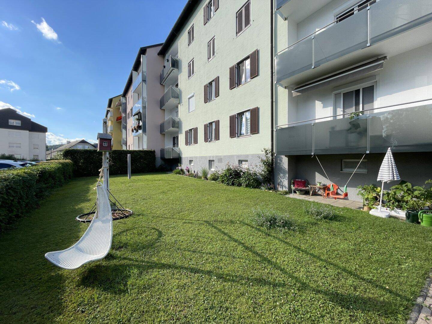 Gepflegter Gartenbereich mit Hängematte und Blick auf die Wohngebäude.