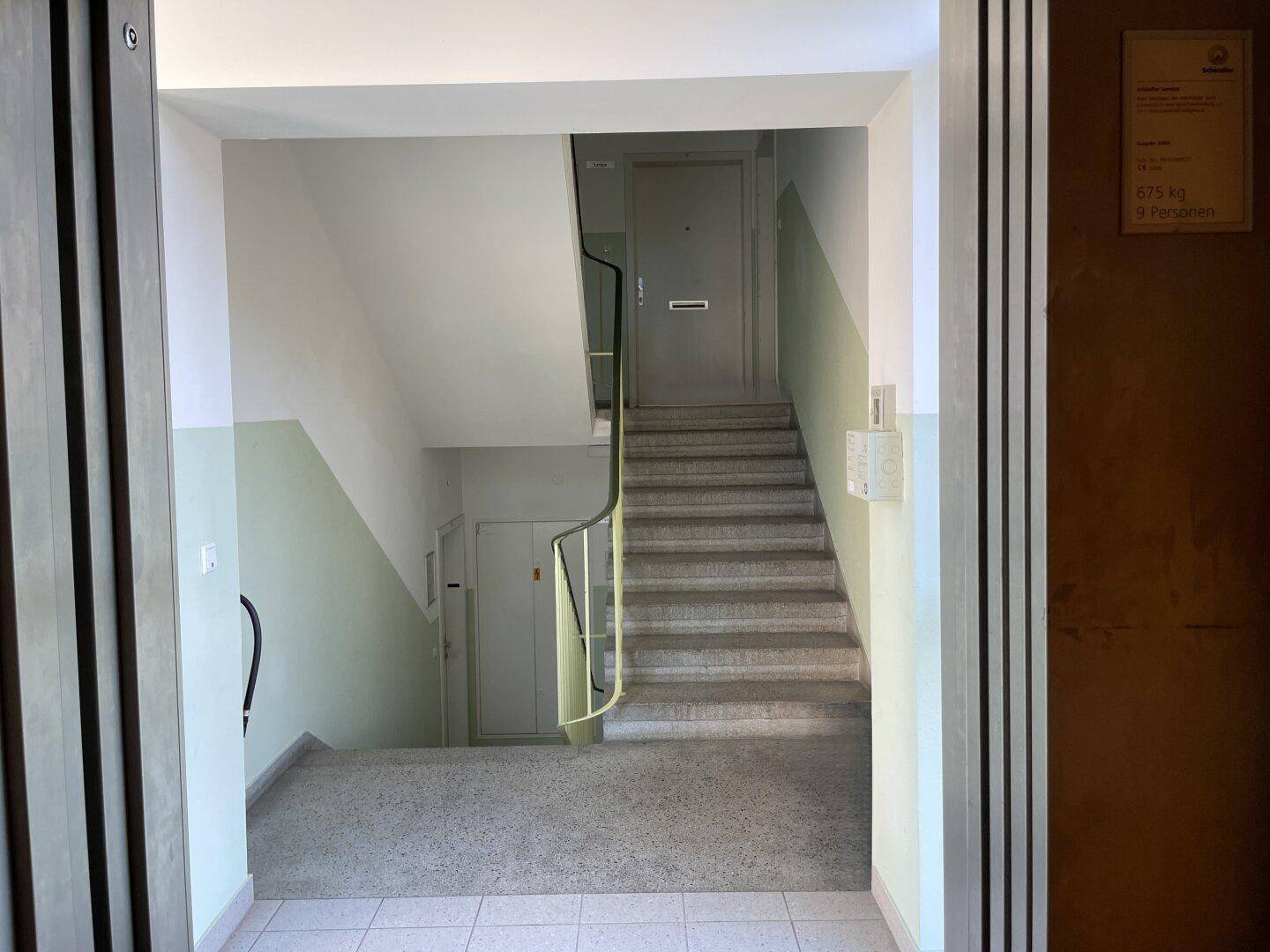 Treppenhaus eines Wohngebäudes mit Steinstufen und schlichtem Geländer.