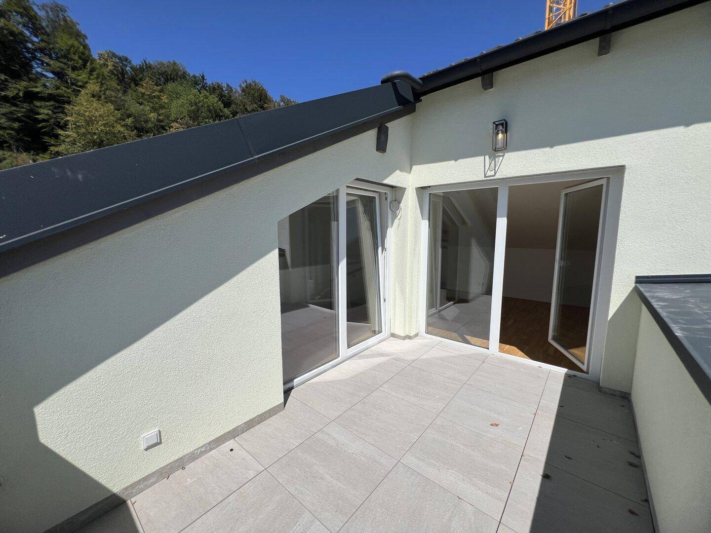 Geräumige Dachterrasse mit Fliesenboden und Blick auf die Umgebung.