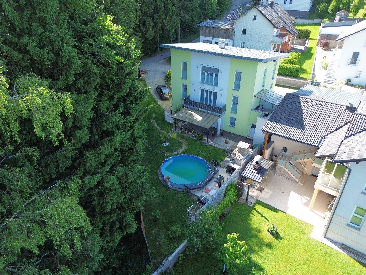 Luftaufnahme des Hauses mit Garten, Pool und umliegender grüner Landschaft.