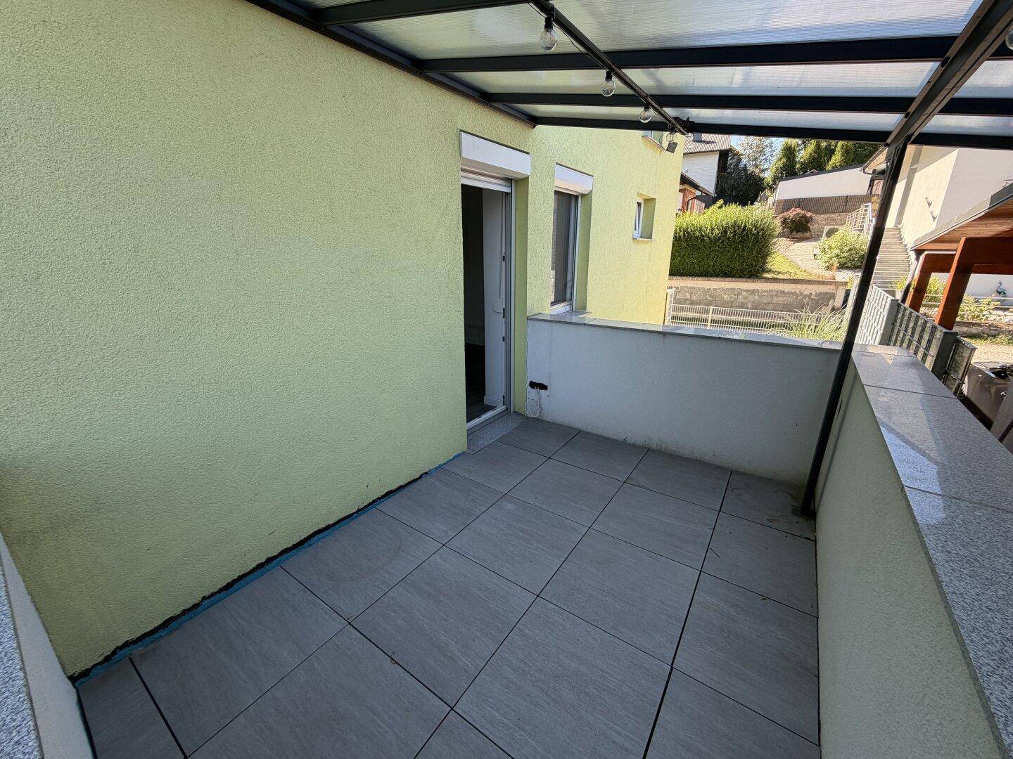 Überdachter Balkon mit Fliesenboden und Blick auf die Umgebung.