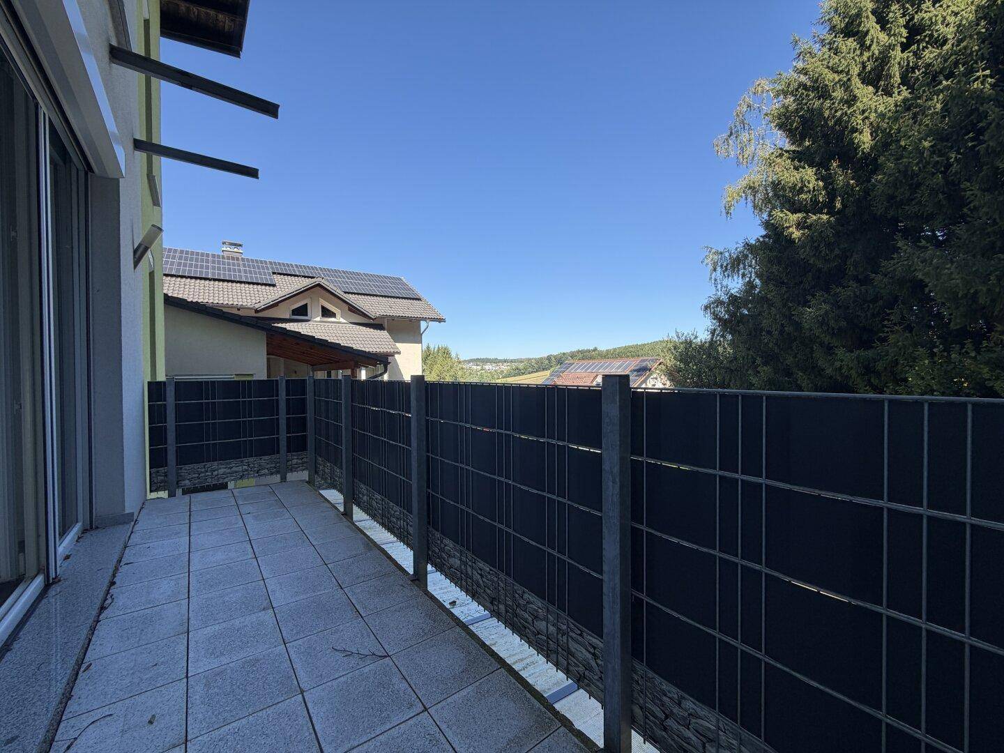 Langer Balkon mit Fliesenboden, Sichtschutz und weitem Blick ins Grüne.