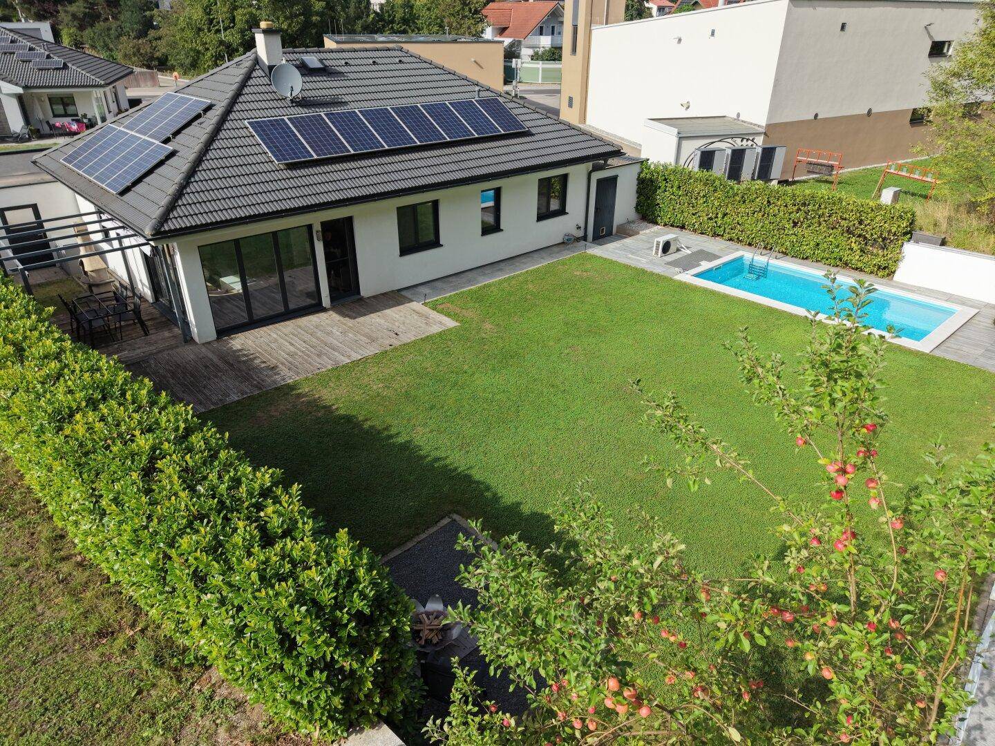 Luftaufnahme des Hauses mit Garten, Poolbereich und Solarmodulen auf dem Satteldach.