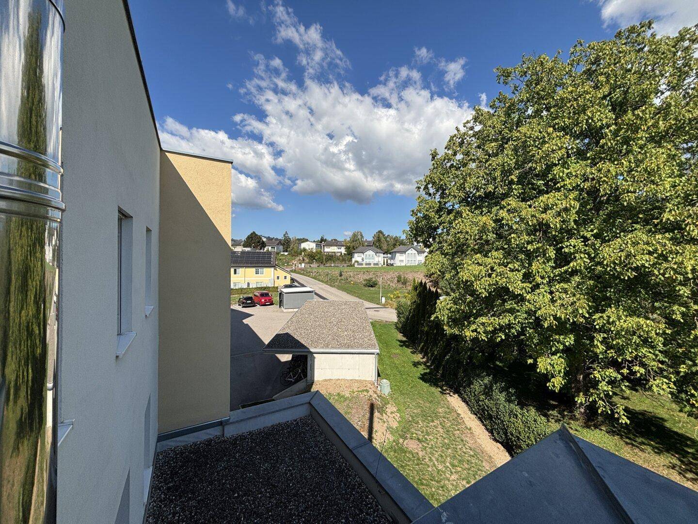 Weitläufiger Blick ins Grüne und auf die umliegende Wohngegend unter blauem Himmel.