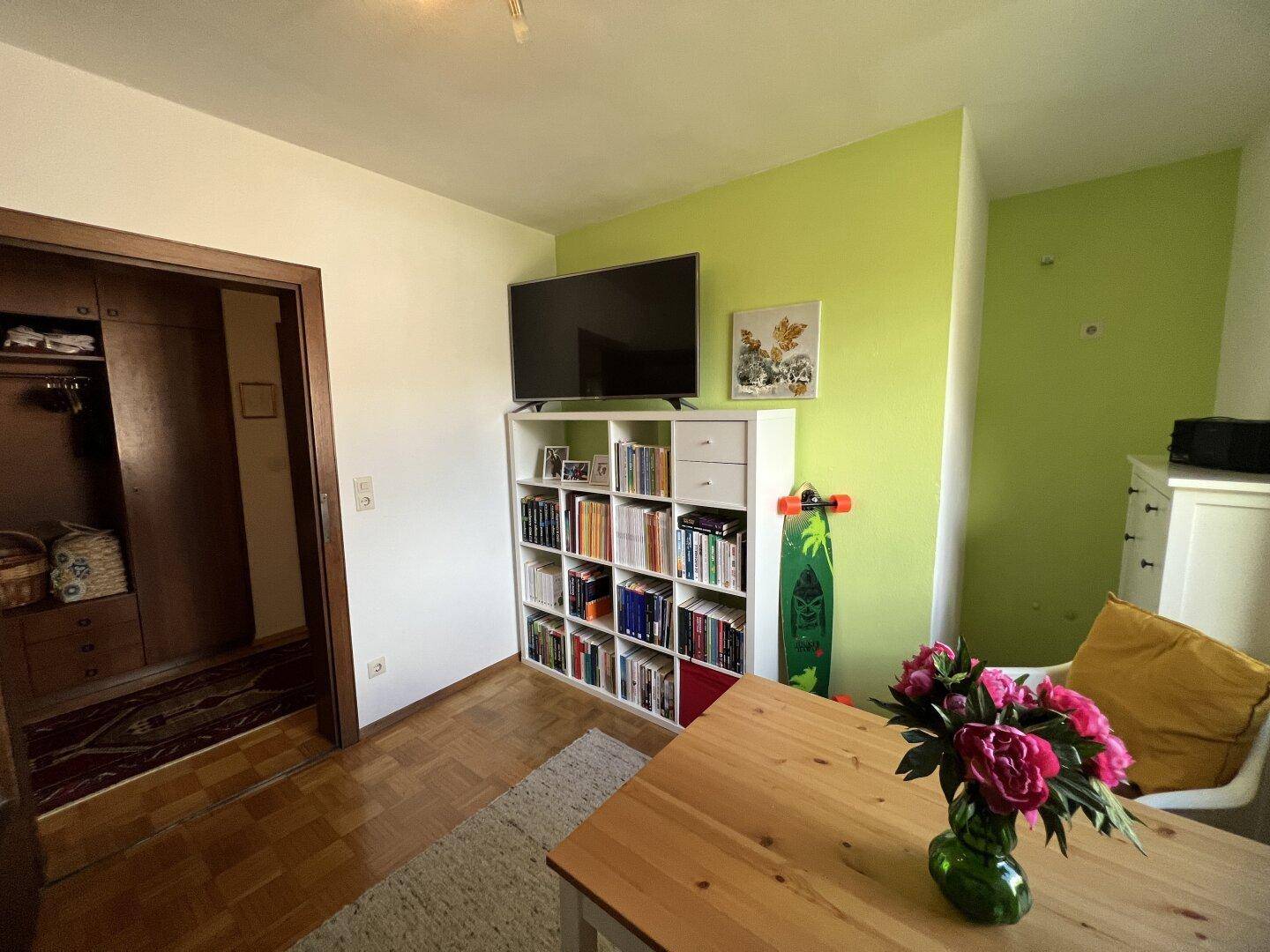 Arbeitszimmer mit viel Stauraum durch ein großes Bücherregal und hellem Ambiente.