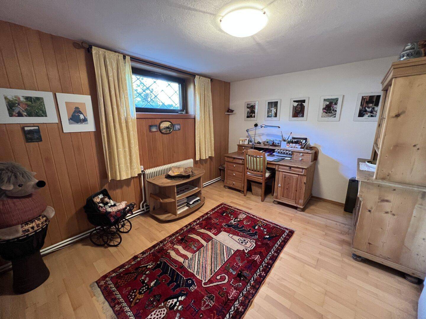 Gemütliches Zimmer mit Holzvertäfelung, Schreibtisch und Teppich, ideal als Büro oder Gästezimmer.