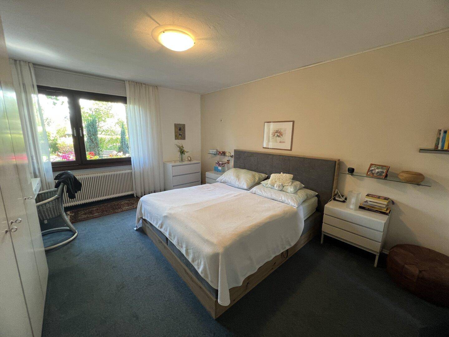 Geräumiges Schlafzimmer mit Doppelbett, Nachttischen und Blick ins Grüne.