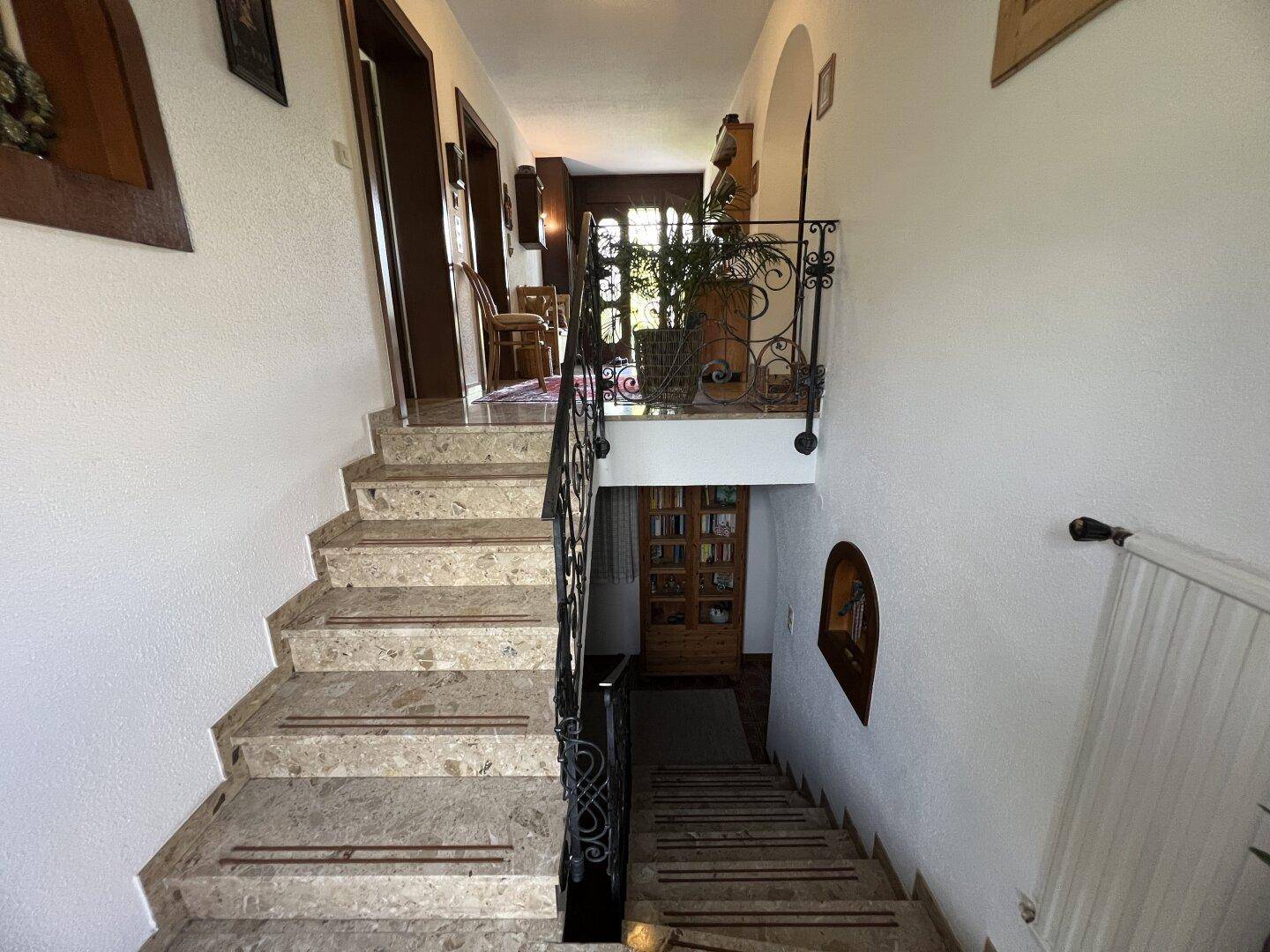 Elegante Steintreppe mit schmiedeeisernem Geländer, die die verschiedenen Etagen verbindet.