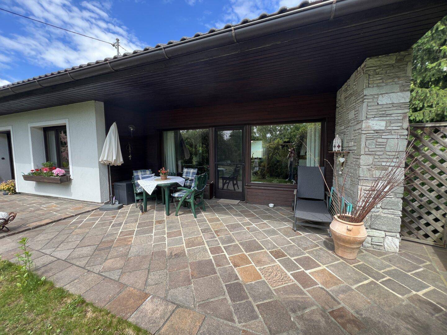 Große gepflasterte Terrasse mit Esstisch und Stühlen, ideal für Mahlzeiten im Freien.