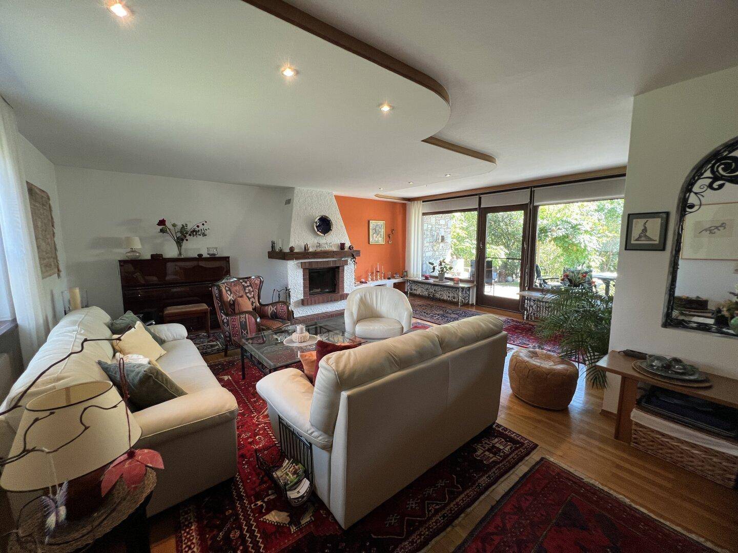 Geräumiges Wohnzimmer mit bequemen Sofas, Kamin und Zugang zum Garten.