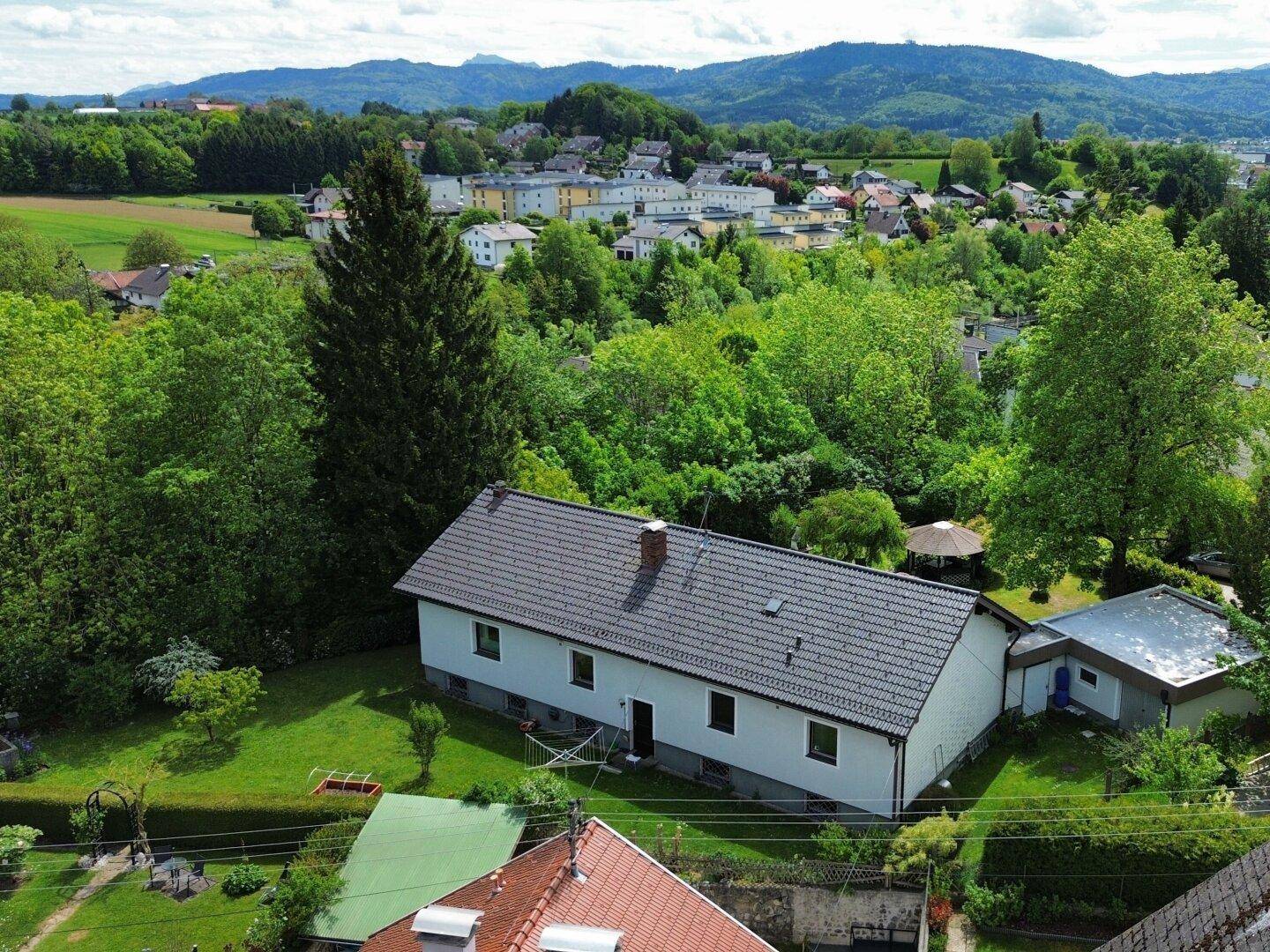 Rückansicht des Hauses mit weitläufigem Garten und Blick auf die umliegende Landschaft.