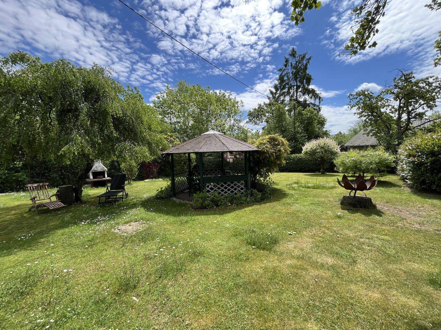Idyllischer Gartenbereich mit Pavillon, Grillplatz und Sitzgelegenheiten für entspannte Stunden im Freien.