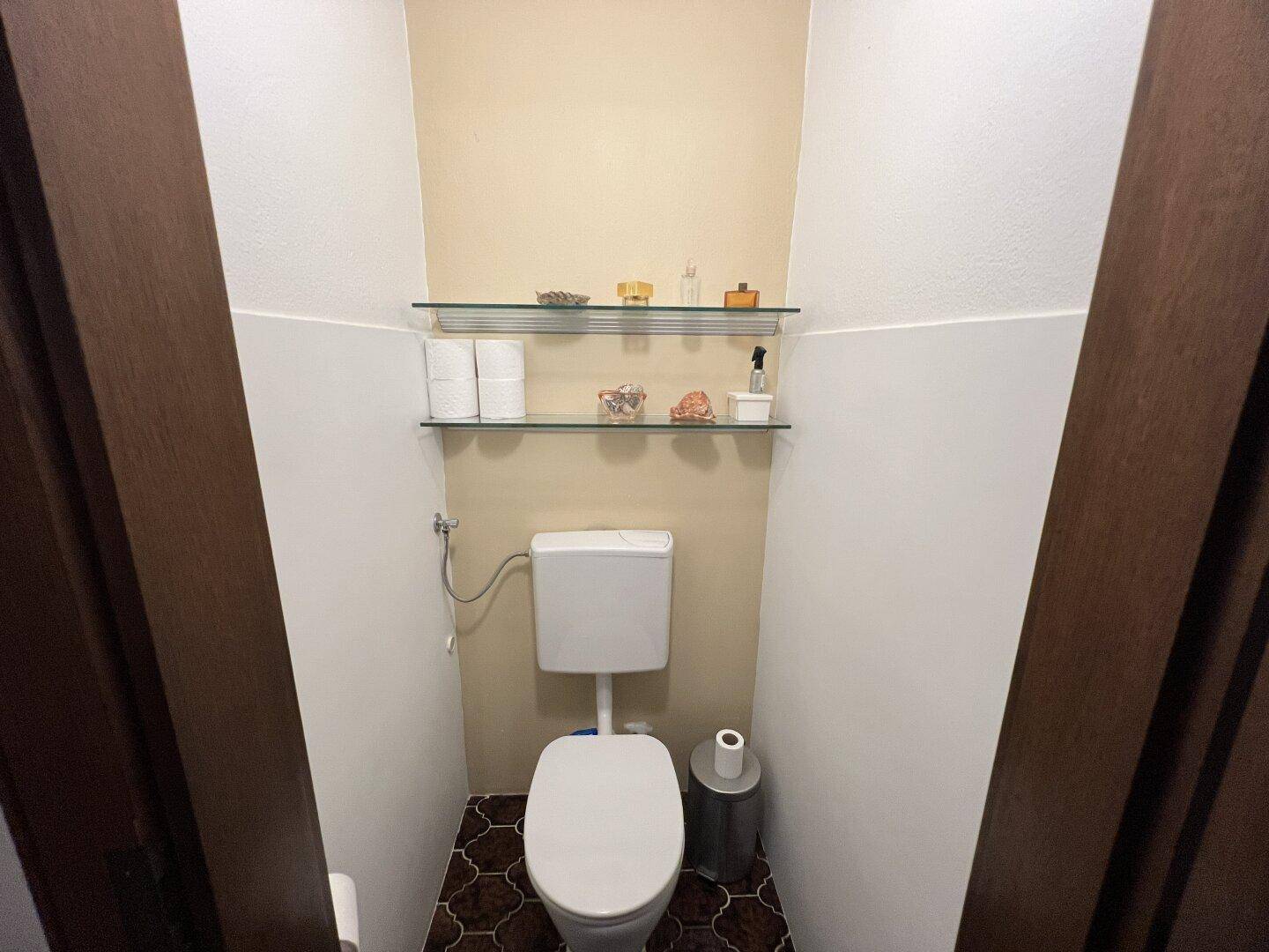 Separates WC mit Toilette und praktischen Ablageflächen.