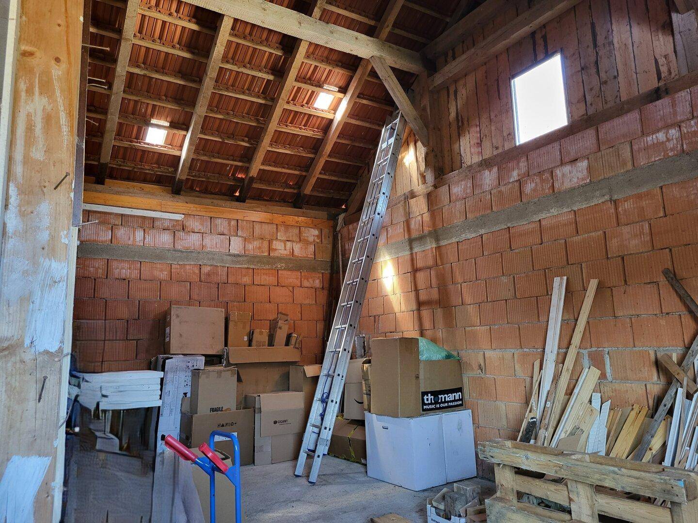 Unausgebauter Dachboden mit sichtbaren Ziegelwänden und Dachkonstruktion.