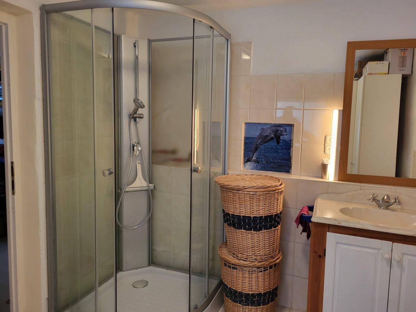 Badezimmer mit Eckdusche, gefliesten Wänden und einem Holzwaschtisch mit integriertem Waschbecken.
