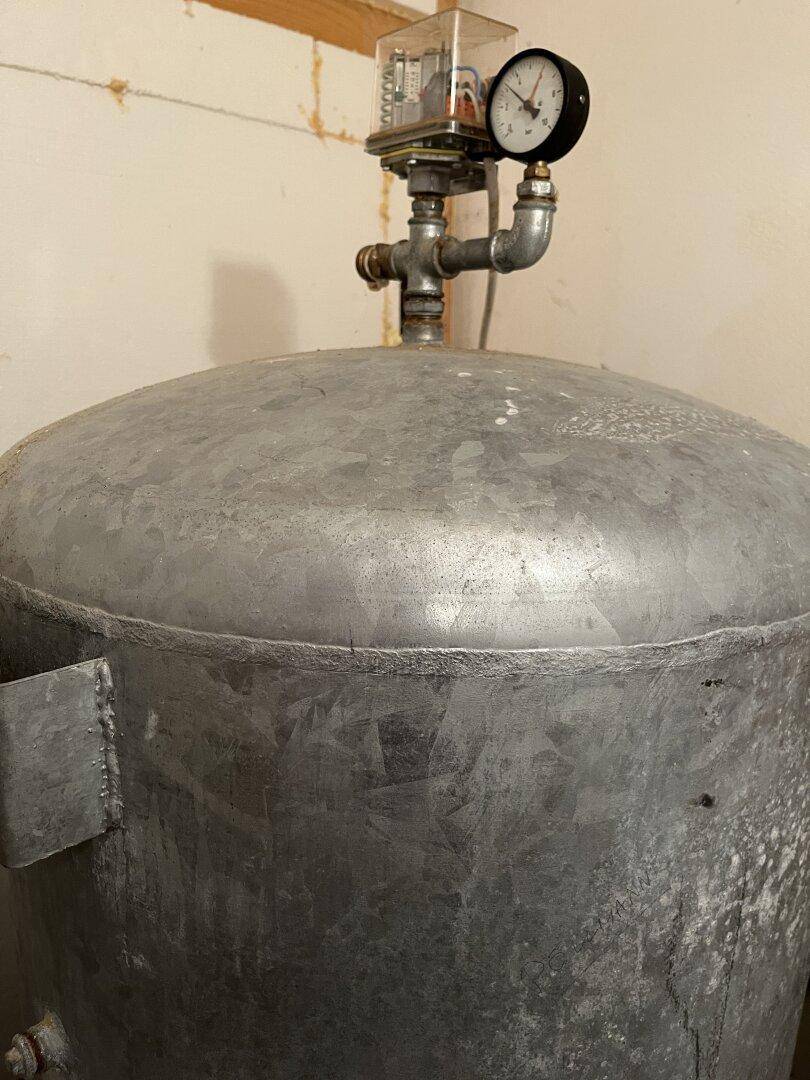 Technischer Raum mit großem Wassertank und Druckanzeige.
