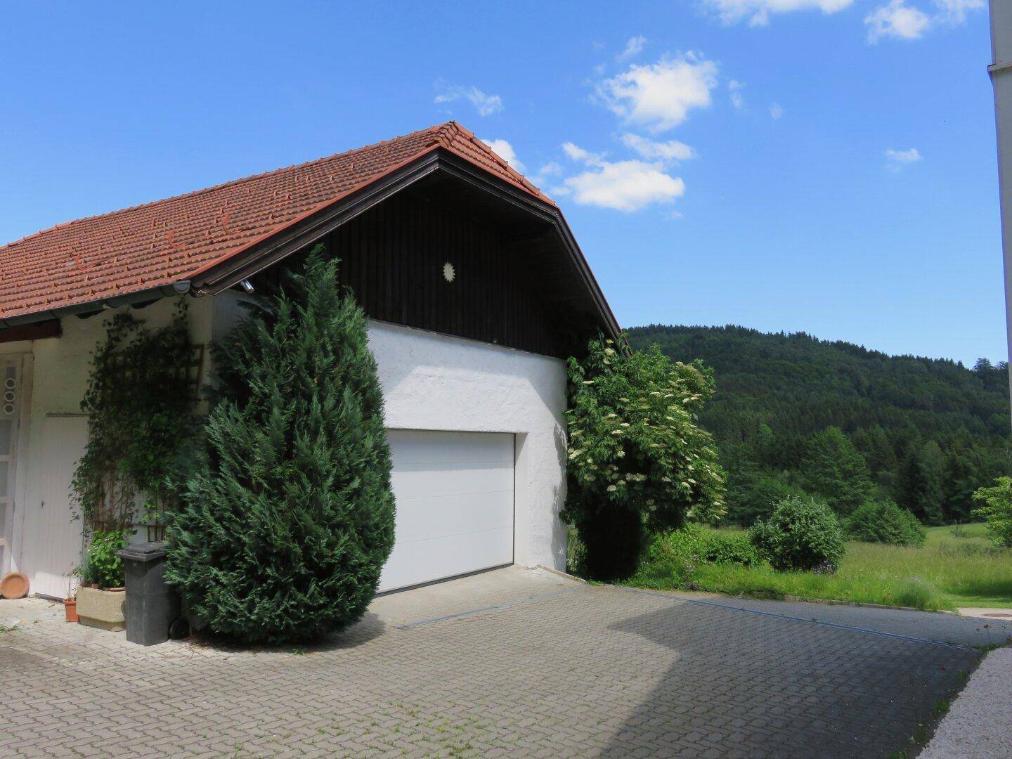 Garage mit gepflasterter Zufahrt und umgebender grüner Landschaft.