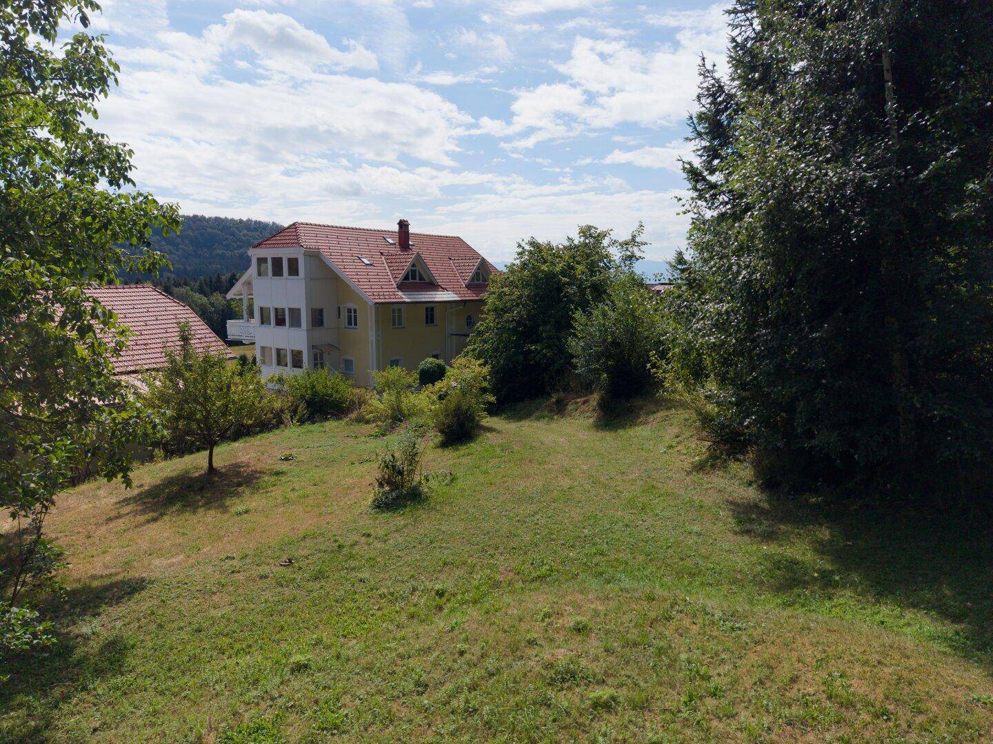 Großes Grundstück mit Wiesenfläche und Blick auf das Hauptgebäude.