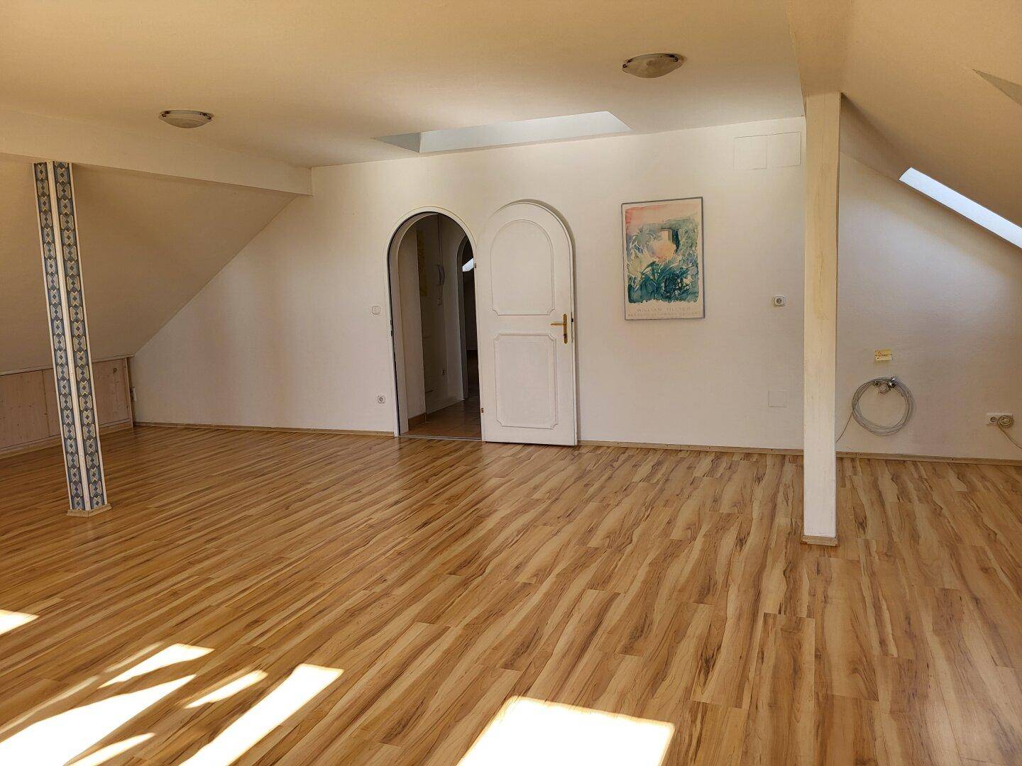 Geräumiges Zimmer im Dachgeschoss mit Laminatboden und Dachschrägen.