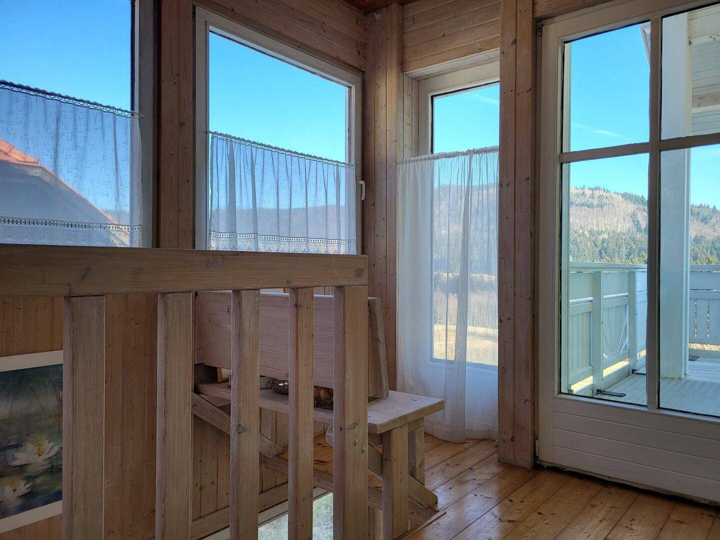 Treppenabsatz oder Flur mit großen Fenstern, Holzboden und einem weiten Blick auf die Berge.