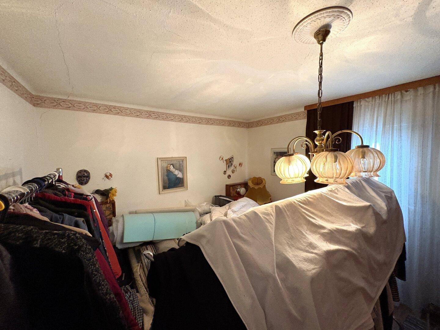 Innenraum mit Kronleuchter, Kleiderständer und traditioneller Tapete.