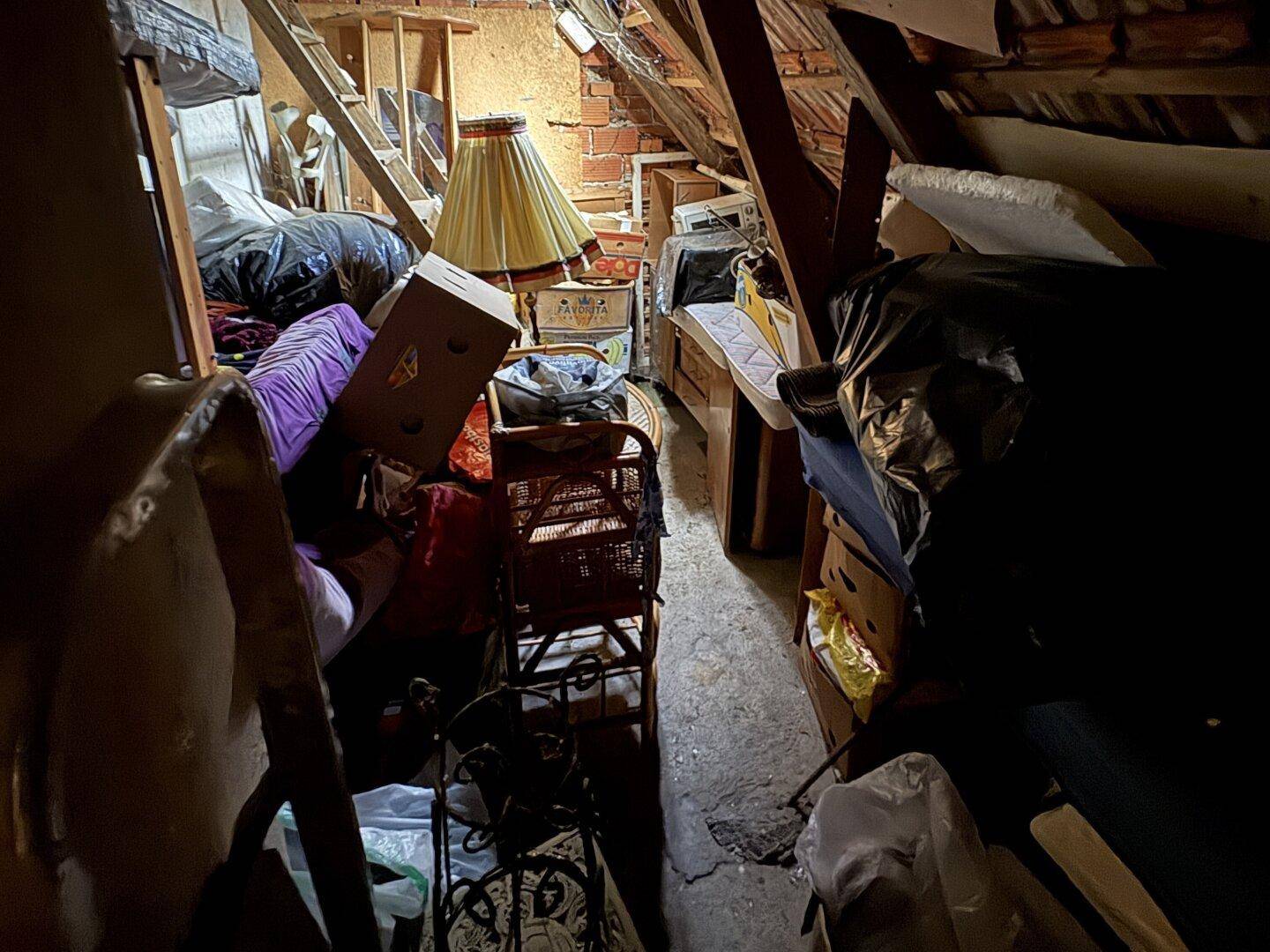 Dachboden als Abstellraum mit sichtbaren Holzbalken und verschiedenen Gegenständen.