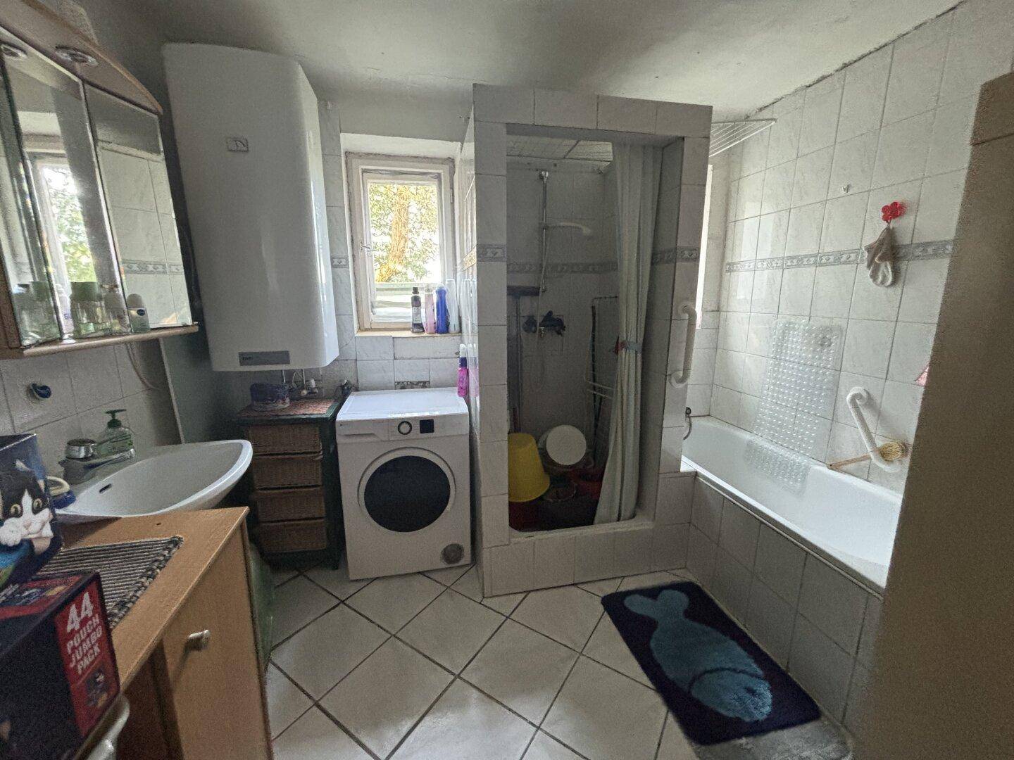 Badezimmer mit Badewanne, Duschkabine, Waschbecken und Waschmaschine.