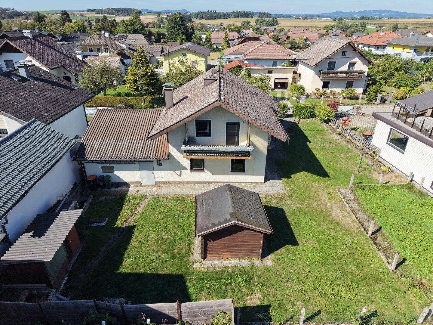 Vogelperspektive des Hauses mit großem Garten, kleinem Schuppen und angrenzenden Nachbargrundstücken.