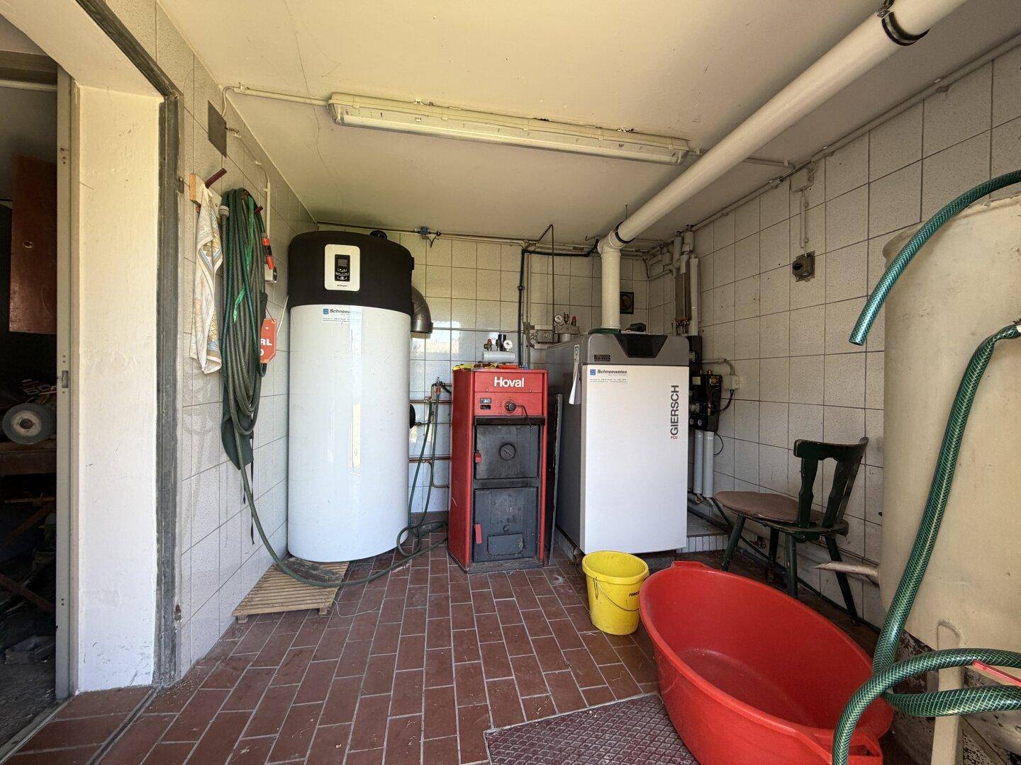 Heizungsraum mit modernen Heizungsanlagen, Warmwasserspeicher und Fliesenboden.