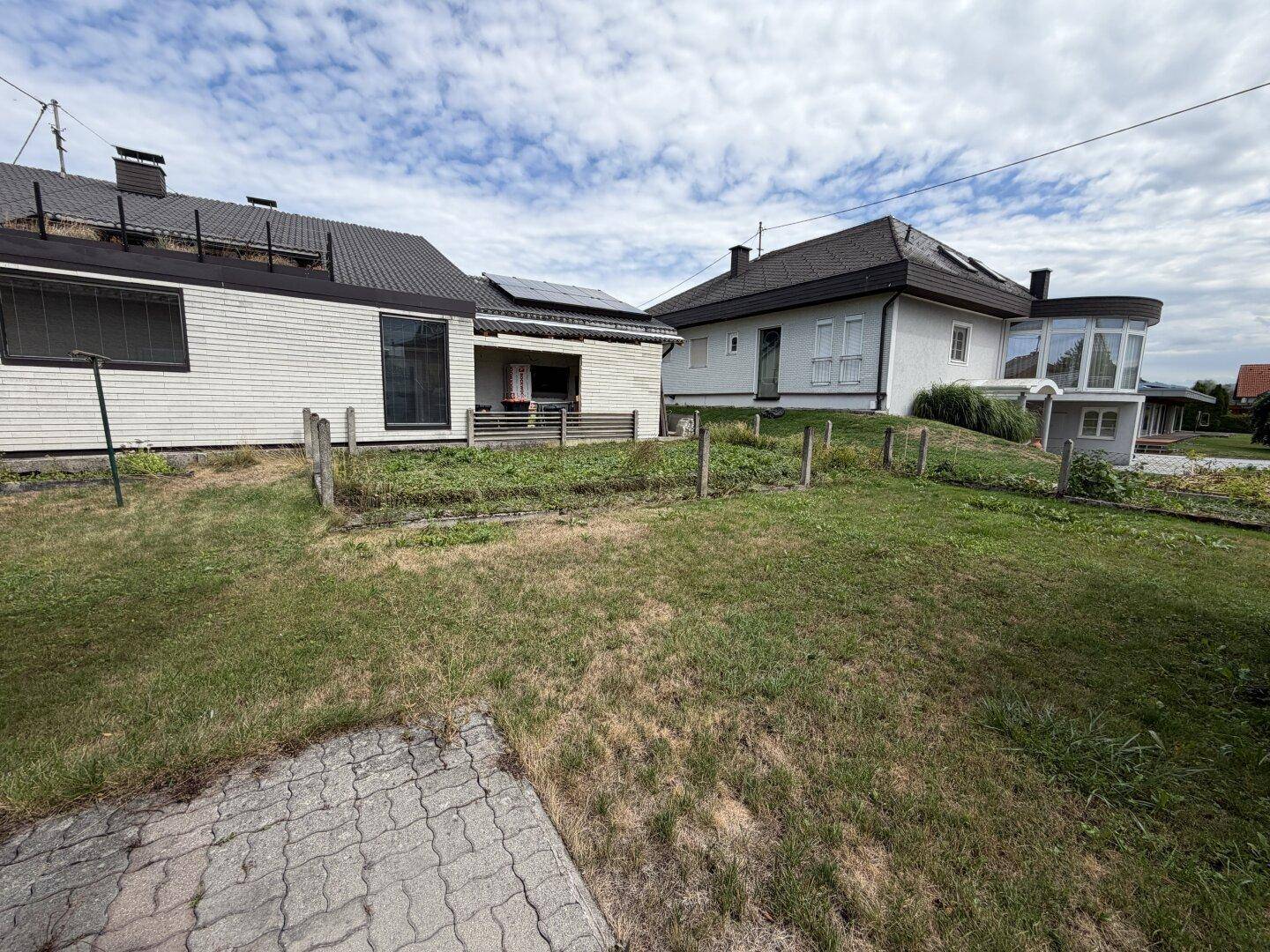 Großer Gartenbereich hinter dem Haus mit Rasenfläche und angrenzenden Nachbargrundstücken.