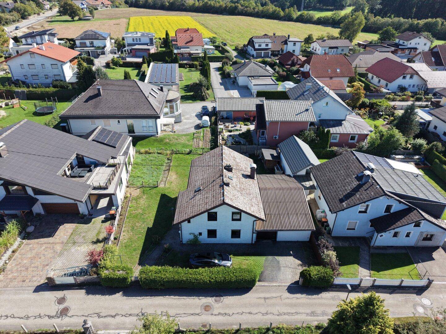 Weitläufige Luftaufnahme einer Wohnsiedlung mit Einfamilienhäusern und angrenzenden Feldern.
